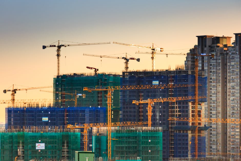 pexels-photo-2138126-2138126 A cityscape featuring high-rise buildings under construction with cranes during sunset.